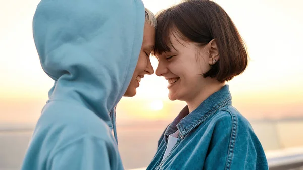 Крупным планом молодая любящая лесбийская пара улыбается во время поцелуя, две женщины наслаждаются романтическими моментами вместе на рассвете — стоковое фото