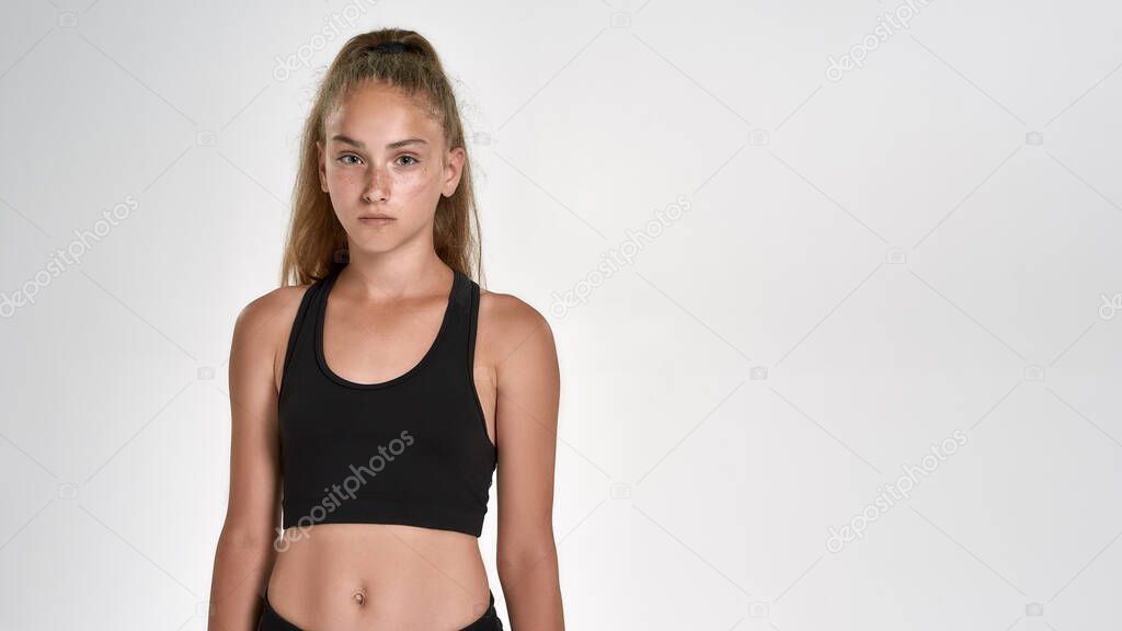 Portrait of cute sportive girl child in sportswear looking at camera, while posing isolated over white background