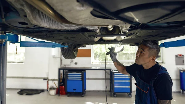 Técnico asiático con linterna en busca de daños en auto — Foto de Stock