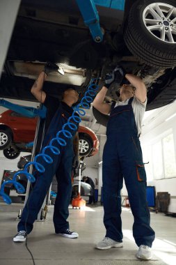 Teknisyenler el feneri ve tornavida kullanarak alt makine ile birlikte çalışıyorlar.