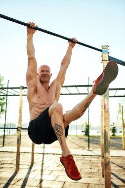 Jimnastik sporcusu yatay çubukta köşe egzersizi yapıyor.