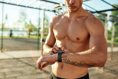 Genç beyaz adam antrenman sırasında akıllı saate bakıyor.