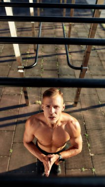 Beyaz tenli genç sporcu eğitim aletlerine bakıyor.