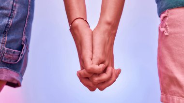 İki kız kardeşin el ele tutuşup mor arka planda izole bir şekilde el ele tutuşması. Destek, birliktelik kavramı