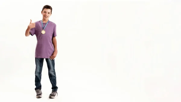 Dlouhý záběr dospívajícího postiženého chlapce s mozkovou obrnou na sobě zlatou medaili, usmívající se a ukazující palce nahoru na kameru izolované přes bílé pozadí — Stock fotografie