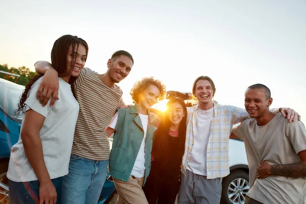 Un grupo de amigos casualmente vestidos de diferentes nacionalidades abrazándose el uno al otro pasándola bien juntos afuera riendo y sonriendo —  Fotos de Stock