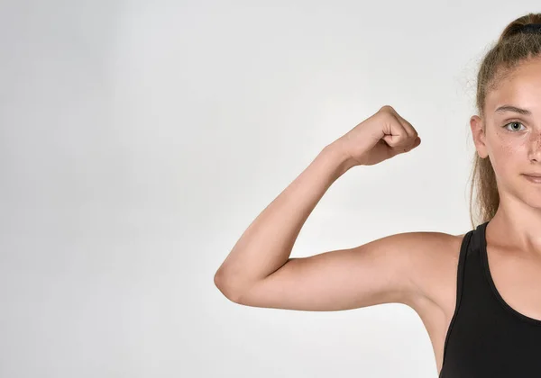 Cortado tiro de menina bonito esportivo criança em sportswear olhando para a câmera, mostrando bíceps ao posar isolado sobre fundo branco — Fotografia de Stock