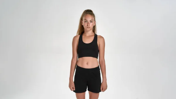 Portrait de fille sportive mignonne enfant en vêtements de sport regardant la caméra, tout en posant isolé sur fond blanc — Photo