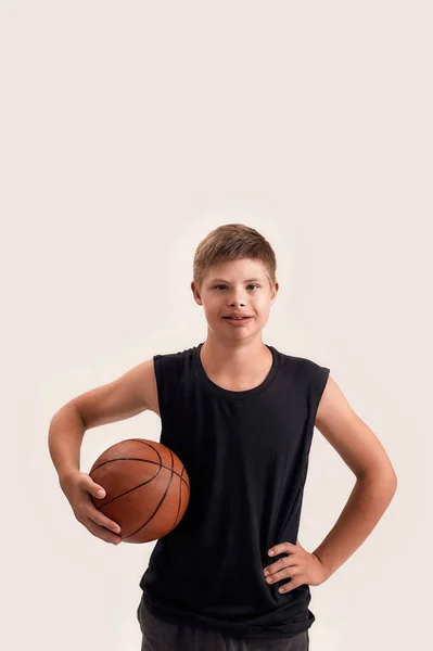 Retrato de niño alegre discapacitado con síndrome de Down mirando a la cámara mientras posa con baloncesto aislado sobre fondo blanco —  Fotos de Stock