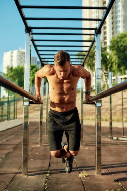 Yakışıklı kaslı beyaz adam paralel parmaklıklara yanaşıyor.