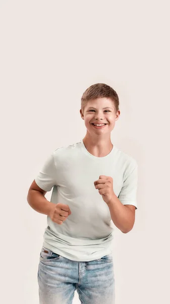 Joyful adolescente deficiente menino com síndrome de Down sorrindo para a câmera enquanto se move para a frente isolado sobre fundo branco — Fotografia de Stock