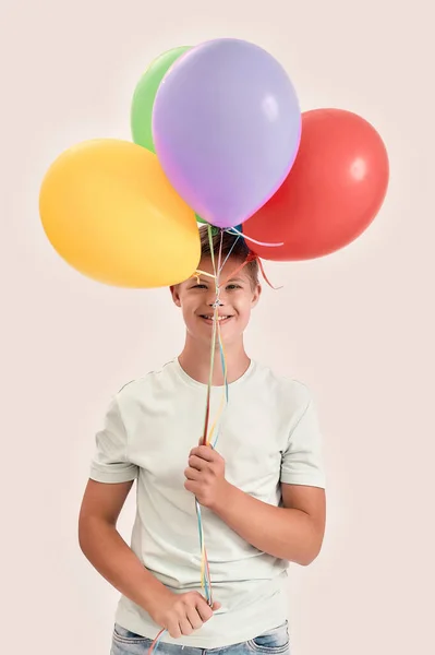 Feliz adolescente discapacitado chico con síndrome de Down sonriendo a la cámara, sosteniendo un montón de globos de colores, mientras que de pie aislado sobre fondo blanco —  Fotos de Stock