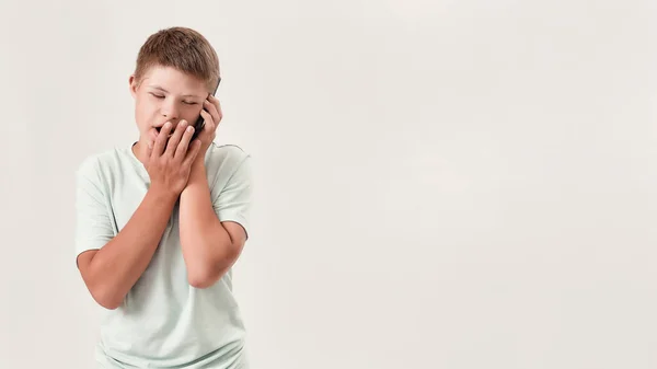 Portrait of teenaged disabled boy with Down syndrome talking on the phone, standing isolated over white background — Stock Photo, Image