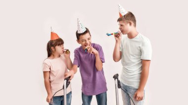 Üç engelli çocuk doğum günü şapkası takıyor, birbirlerine bakıyor ve birlikte doğum günlerini kutlarken ıslık çalıyorlar.