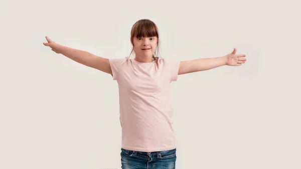 Retrato de menina com deficiência com síndrome de Down sorrindo para a câmera enquanto em pé com os braços estendidos isolados sobre fundo branco — Fotografia de Stock