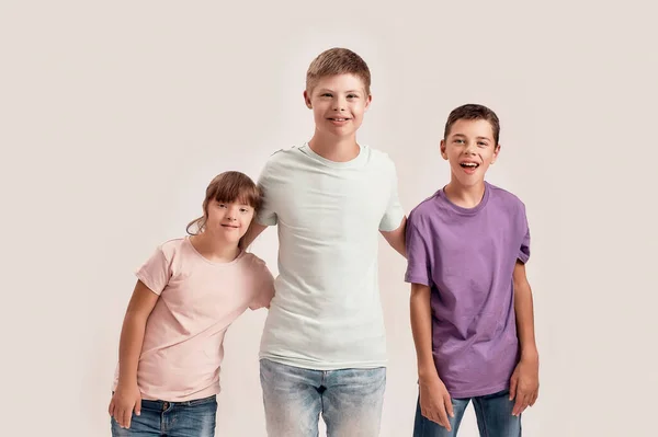 Three cheerful teenaged disabled children with Down syndrome and cerebral palsy smiling at camera while posing together isolated over white background — Stock Fotó