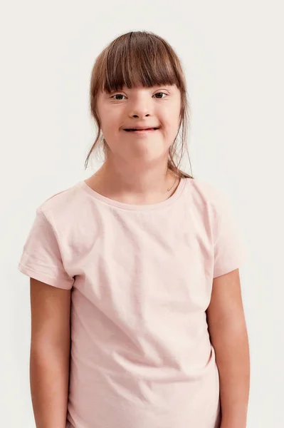 Retrato de menina com deficiência com síndrome de Down sorrindo para a câmera enquanto posando isolado sobre fundo branco — Fotografia de Stock