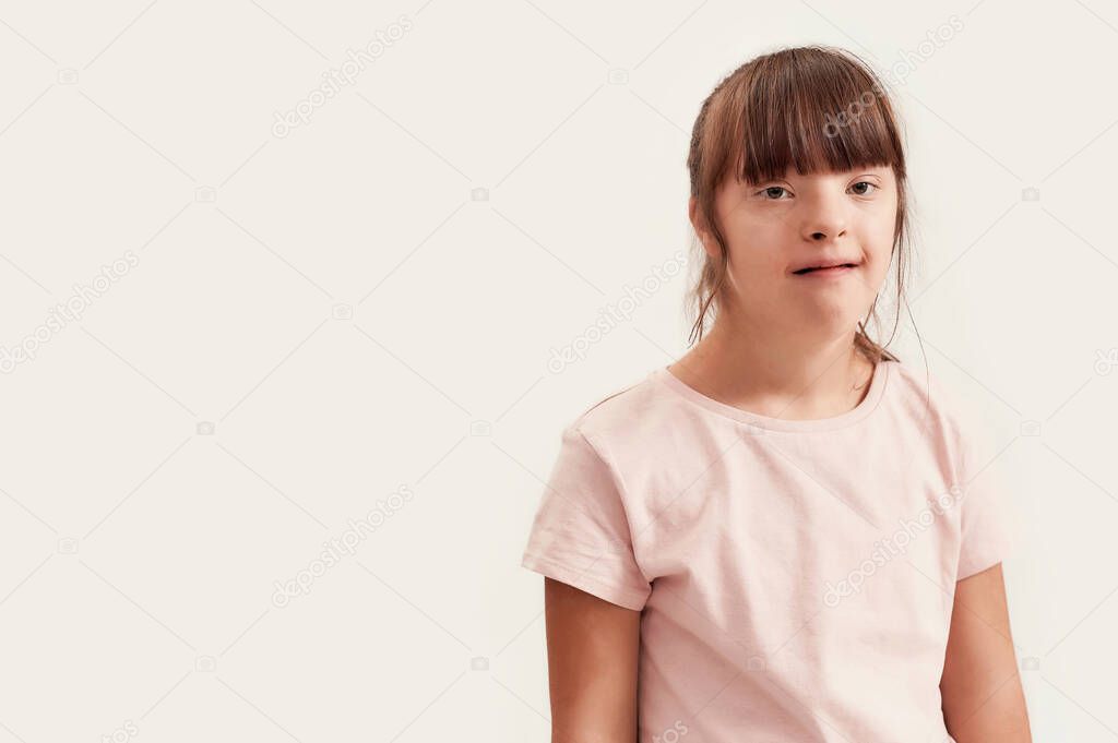 Portrait of disabled girl with Down syndrome looking at camera while posing isolated over white background