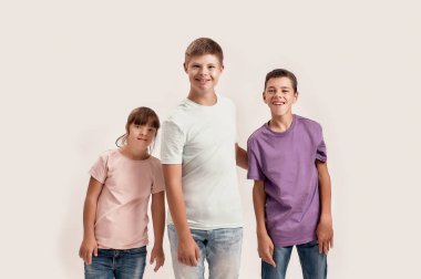 Down sendromu ve beyin felci olan üç neşeli genç, beyaz arka planda izole bir şekilde poz verirken kameraya gülümsüyor.