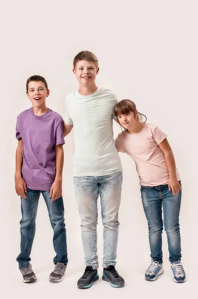 Full length shot of three cheerful teenaged disabled children with Down syndrome and cerebral palsy smiling while standing together isolated over white background — Stock Photo, Image