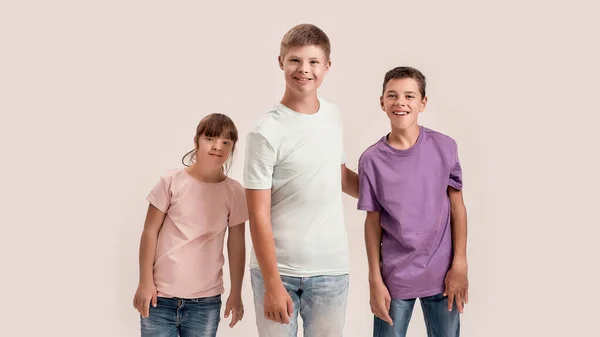 Tre bambini disabili adolescenti con sindrome di Down e paralisi cerebrale che sorridono alla telecamera mentre posano insieme isolati su sfondo bianco — Foto Stock