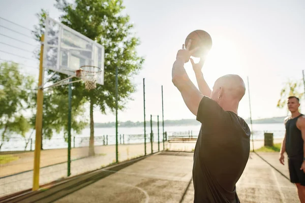 Close up of man holding basketball while playing outdoors together with his friends on a sunny day — Stok Foto