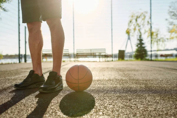 Close up of legs of young male basketball player in sportswear standing on the court with basketball during Covid19 pandemic — Stok Foto