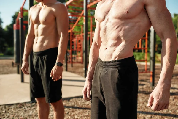 Close up of muscular body of male bodybuilder with naked torso exercising at street gym yard. Sportive men training muscles outdoors — Stock Photo, Image