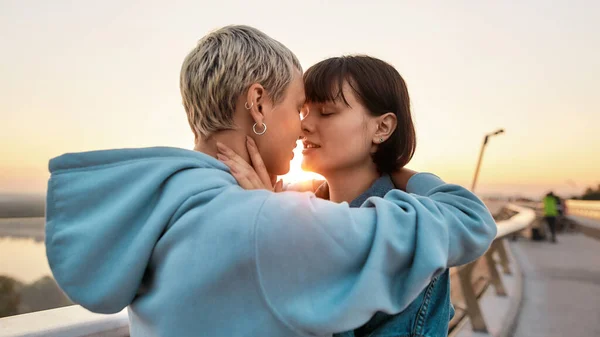 Fiatal, szenvedélyes leszbikus pár fog csókolózni, két nő, akik együtt élvezik a romantikus pillanatokat napkeltekor. — Stock Fotó