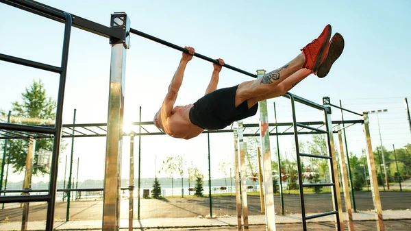 Homem forte fazendo exercício estático na barra horizontal — Fotografia de Stock