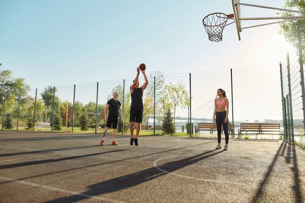 Orang terampil mempersiapkan diri untuk melempar bola ke dalam keranjang, sementara menghabiskan waktu dengan teman-temannya di luar ruangan di taman bermain, bermain basket — Stok Foto