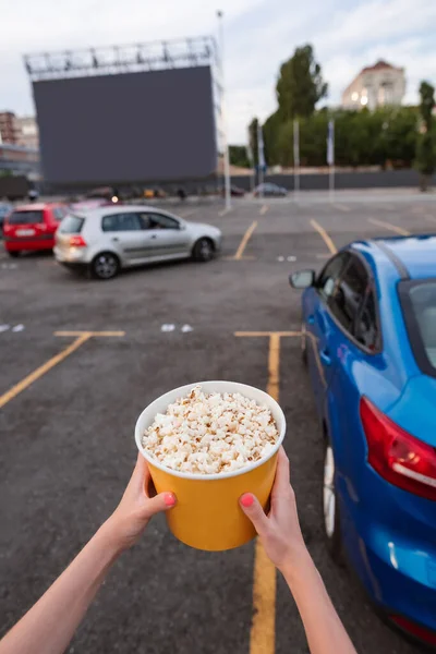 Großer Popcorn-Eimer in Mädchenhand auf Autokino-Parkplatz — Stockfoto