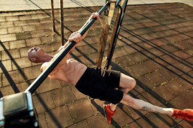 Yatay çubuktaki kaslı sporcuya yukarıdan bak