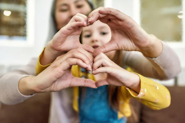 Répandez l'amour. Petite-fille et sa grand-mère aimante montrant signe du cœur tout en passant du temps ensemble à la maison — Photo