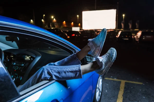 차 앞 좌석에서 영화를 보고 있는 여성의 다리를 차창 밖으로 내동 댕이쳐내고 있는 모습 — 스톡 사진