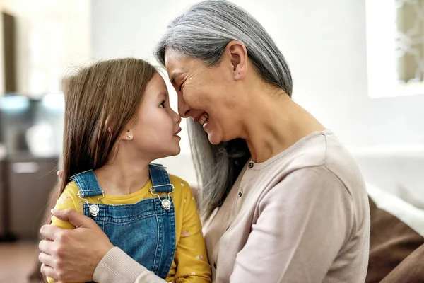 The love of a grandma. Portrait of loving grandmother and joyful granddaughter looking at each other with love while spending time together at home