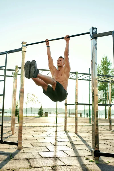 Handsome caucasian athlete performing corner exercise on horizontal bar — Stock Photo, Image