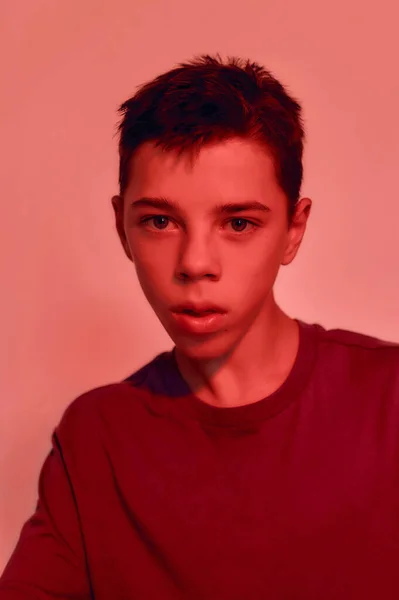 Közelkép portré tinédzser fogyatékos fiú agyi bénulás néz félre, pózol elszigetelt piros fény háttér — Stock Fotó