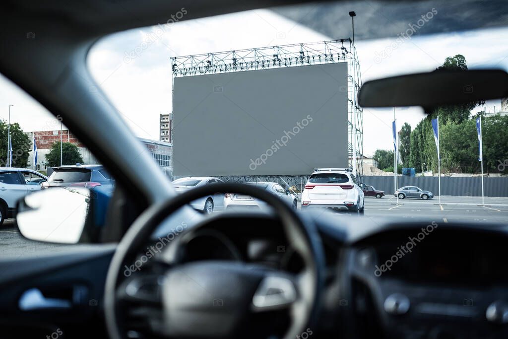 Autocinema screen viewed through front window car