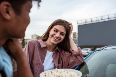 Genç beyaz kız otosinemada bir erkekle eğleniyor.