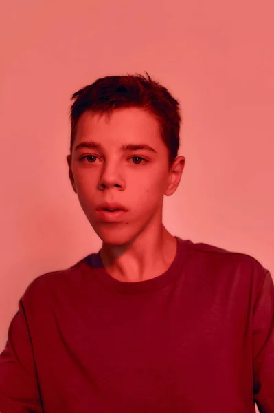 Close up portrait of teenaged disabled boy with cerebral palsy looking away, posing isolated over red light background — Stock Photo, Image