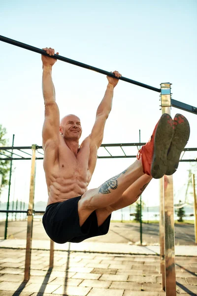 Male athlete doing corner exercise on horizontal bar — Stock Photo, Image
