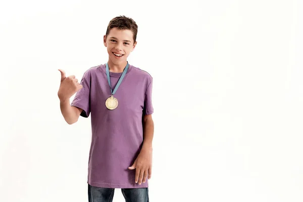 Joyeux garçon handicapé adolescent avec paralysie cérébrale portant la médaille d'or, souriant et montrant les pouces vers le haut à la caméra, debout isolé sur fond blanc — Photo
