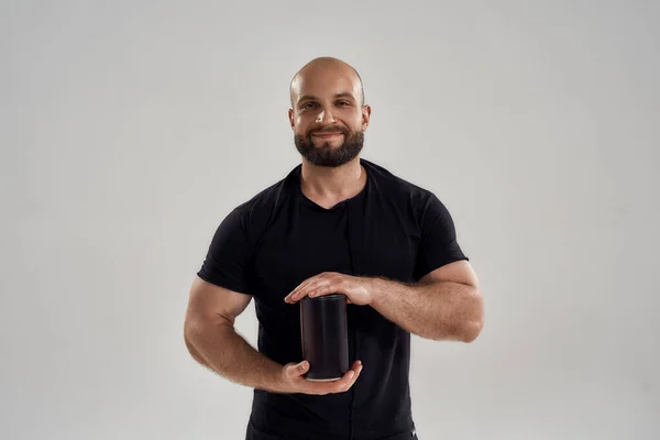Sorridente giovane uomo caucasico muscolare che mostra bottiglia di proteine — Foto Stock