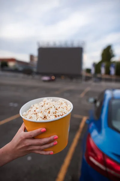 Frau hält großen gelben Popcorn-Eimer im Autokino — Stockfoto