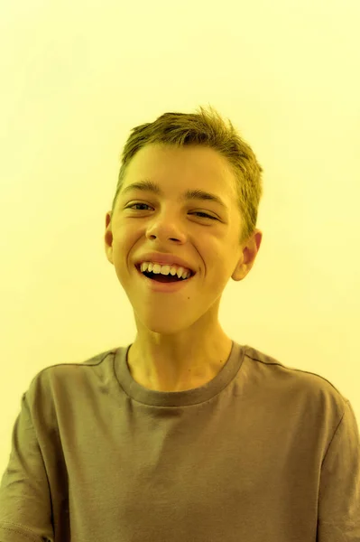 Gros plan portrait d'un adolescent handicapé joyeux avec une paralysie cérébrale souriant à la caméra tout en posant isolé sur fond de lumière jaune — Photo