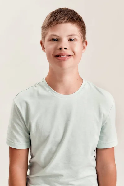 Retrato de menino desativado alegre com síndrome de Down sorrindo para a câmera enquanto posando isolado sobre fundo branco — Fotografia de Stock