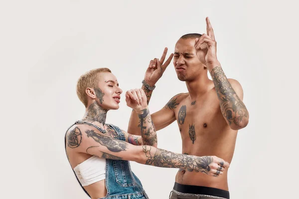 Relação multicultural. Uma menina tatuada branca perfurada e um homem de topless de pele escura com tatuagens ambos dançando se divertindo juntos — Fotografia de Stock