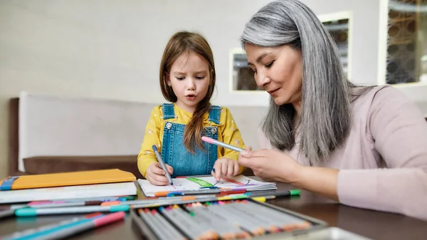 Lindo dibujo nieta en el álbum cerca de la abuela —  Fotos de Stock