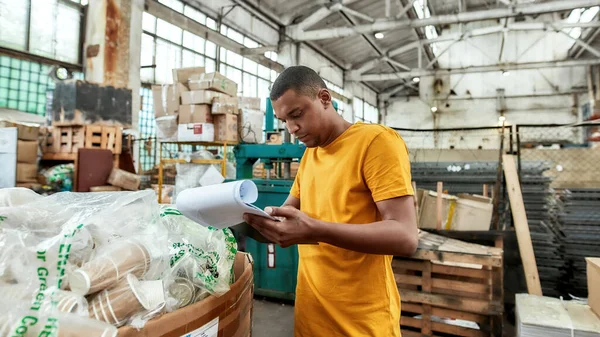 Young african american worker checking data about rubbish — Stock Photo, Image